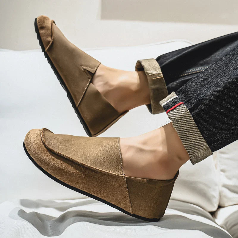 Brown loafers worn with rolled-up jeans on a light background